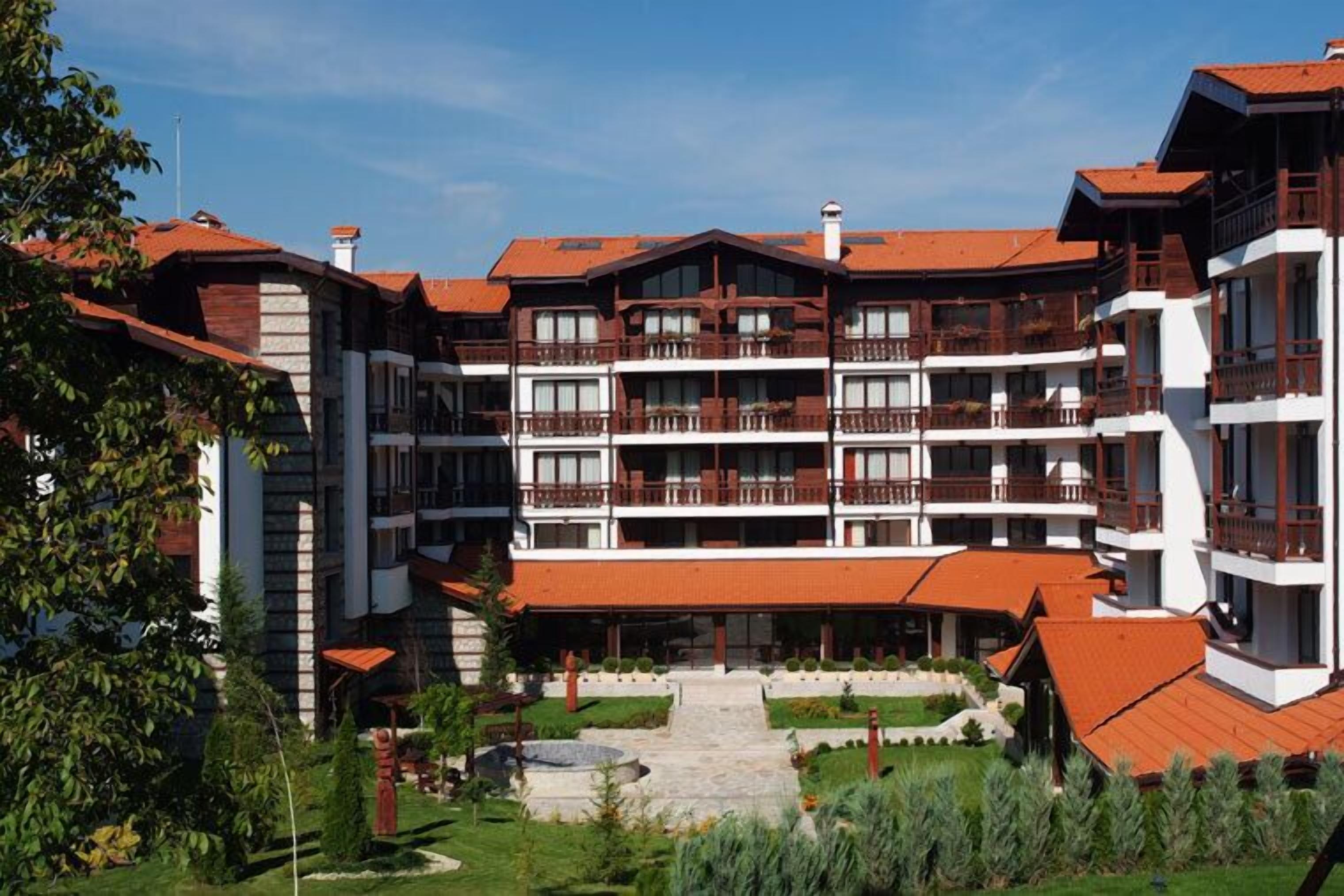 Un hotel de varios pisos con balcones, un patio central y un techo de tejas rojas.