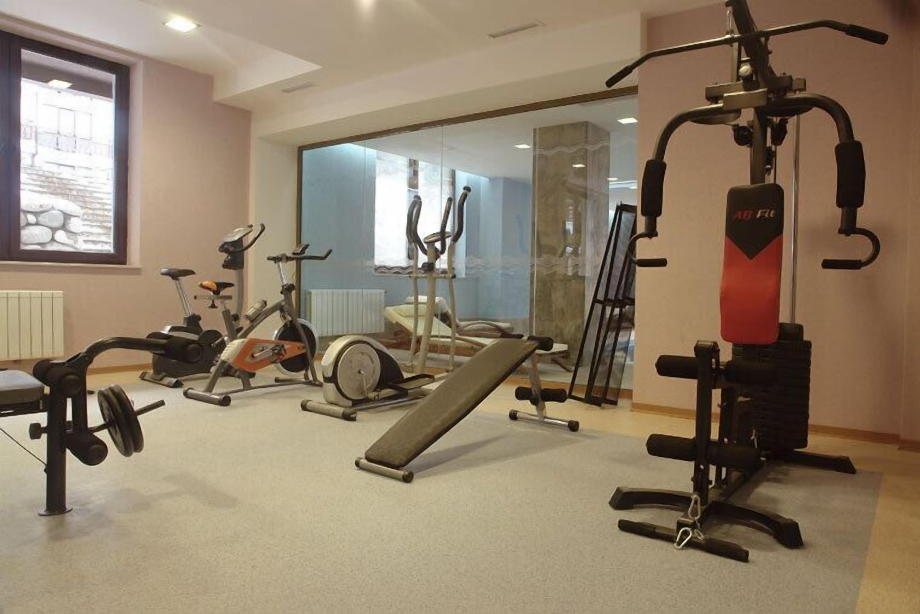 A gym with various exercise equipment including a bench, elliptical, and weight machines.