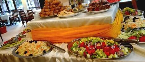 A buffet table with various dishes including salads, meats, and desserts.