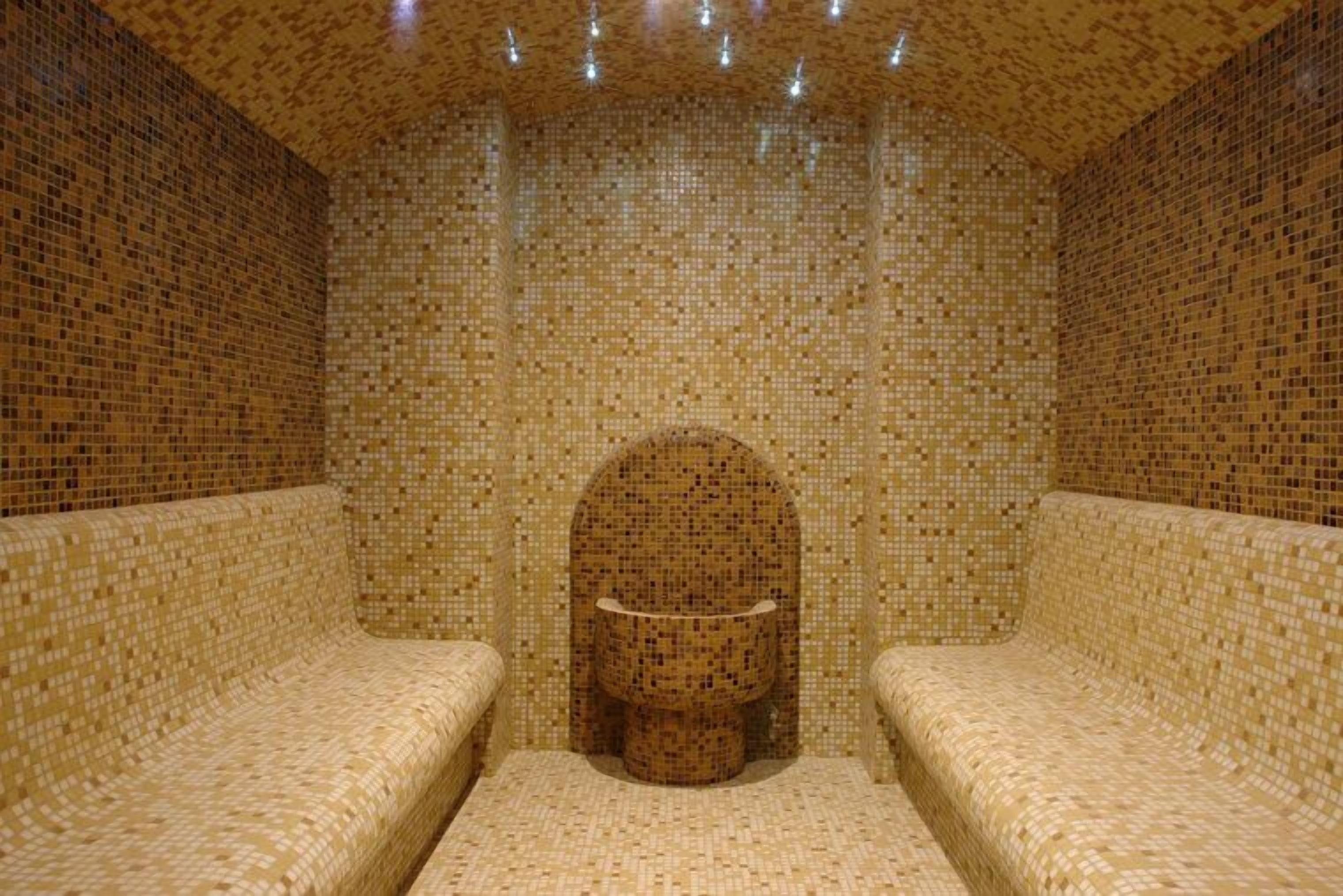 Una habitación con paredes cubiertas de mosaicos y bancos.
