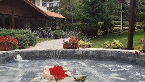 A courtyard with a fountain, surrounded by potted plants and flowers.