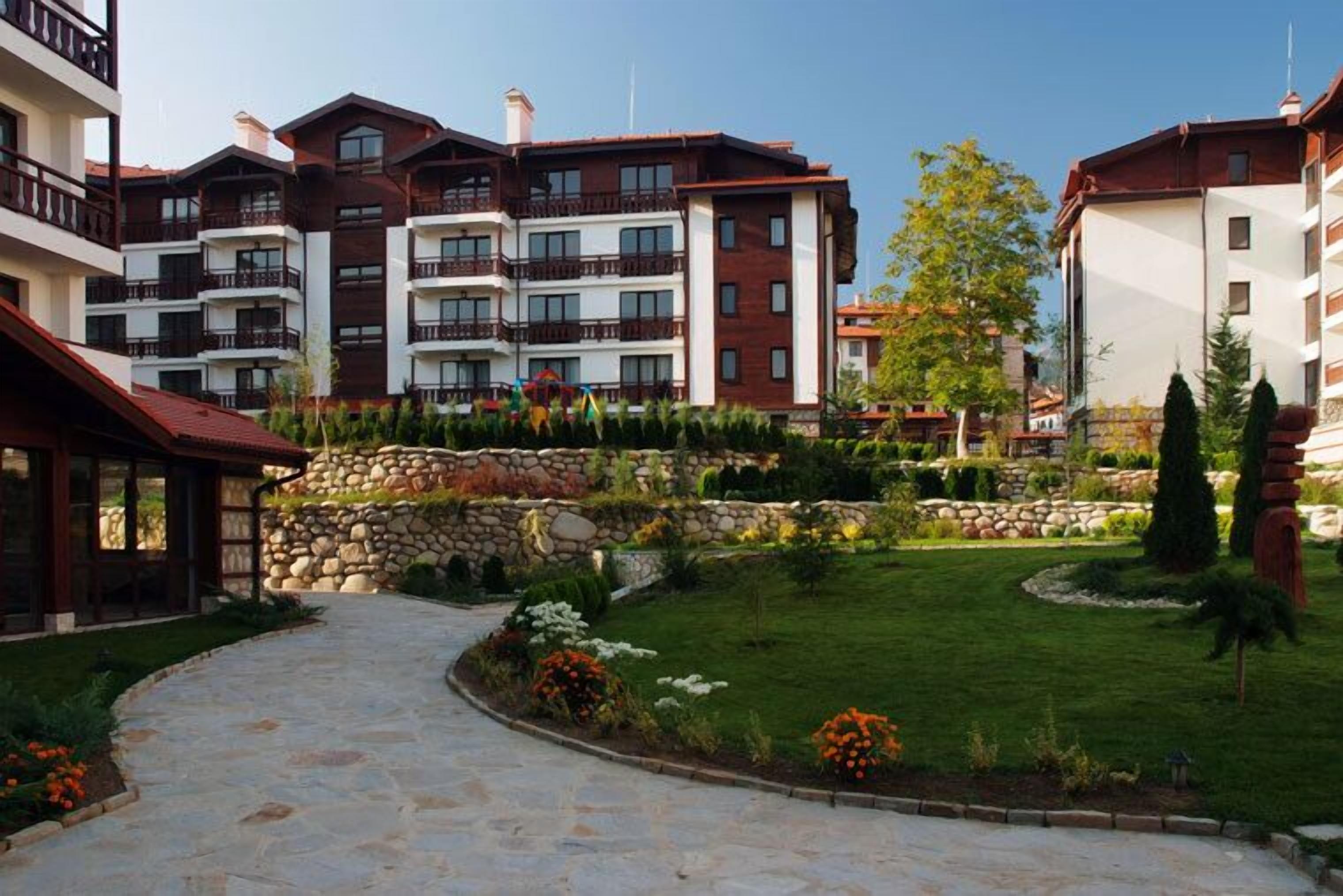 A multi-story hotel with balconies, a stone pathway, and a well-maintained garden.