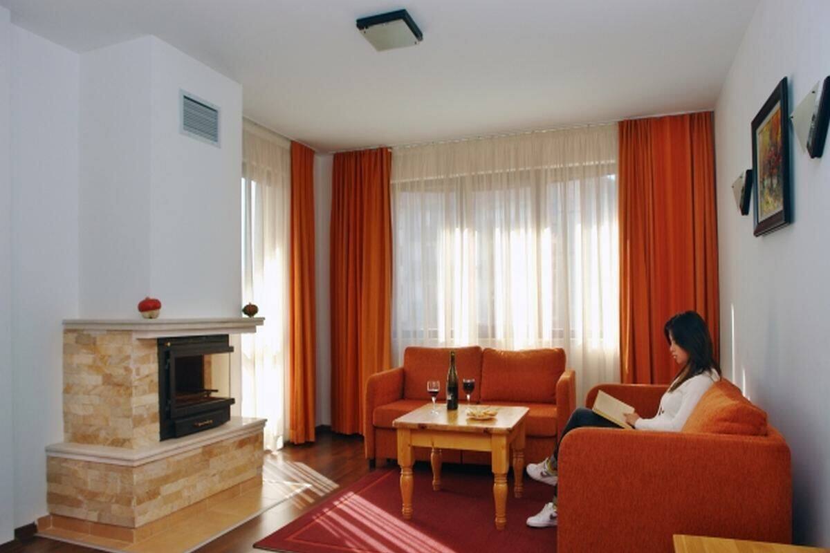 A living room with a fireplace, a sofa, a coffee table, and a person reading a book.