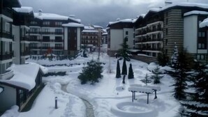 A snow-covered courtyard with modern buildings, a central pathway, and snow-covered trees.