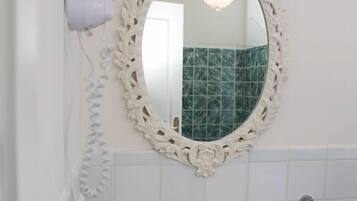 A bathroom with a white sink, a mirror with an ornate frame, and a hairdryer on the wall.