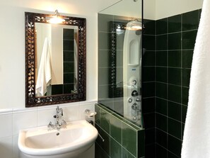 A bathroom with a white sink, a decorative mirror, and a glass-enclosed shower. - Hotel Rústico A Torre de Laxe (Laxe)