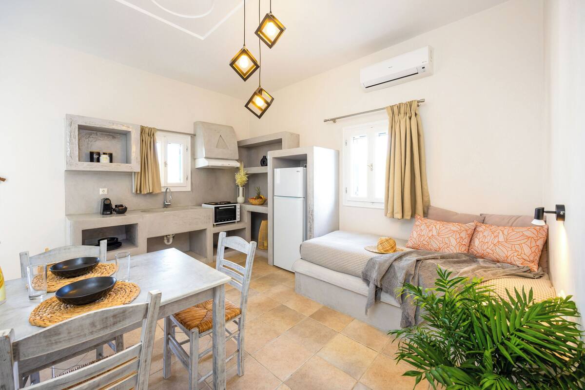 A compact living space with a kitchenette, dining area, and a cozy seating area with a sofa and cushions.