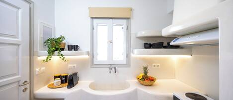 Una cocina compacta con un lavamanos, estufa y una ventana sobre el lavamanos.