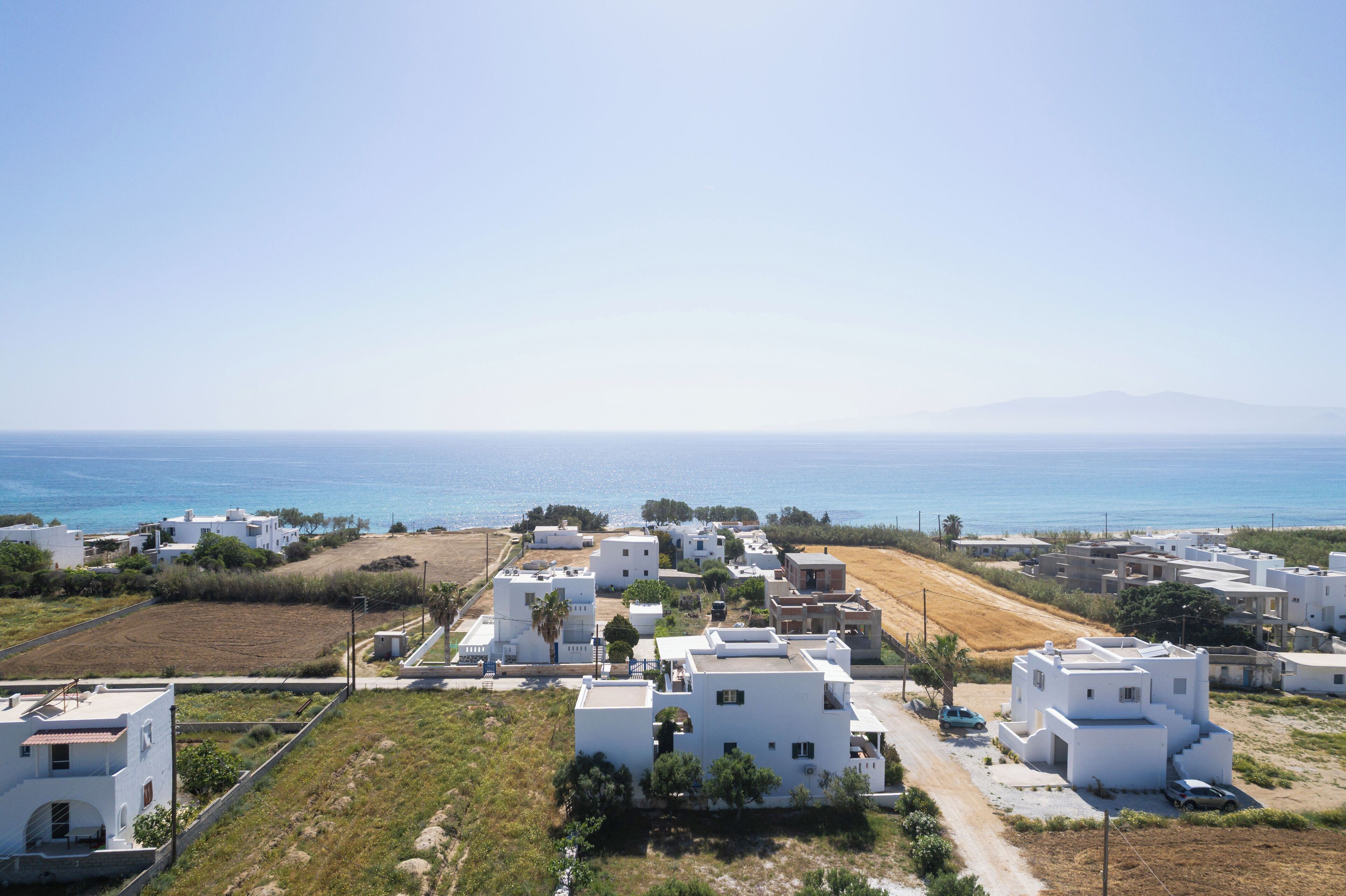 Une zone résidentielle côtière avec des bâtiments blancs, un ciel bleu dégagé et la mer en arrière-plan.