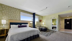 Une chambre d’hôtel avec un grand lit, un bureau, une chaise, un canapé et un miroir.