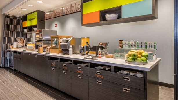 Un espace cuisine moderne doté d’un bar pour prendre le petit-déjeuner, intitulé « table d’inspiration », et comprenant une machine à café, un grille-pain et divers éléments pour le petit-déjeuner.