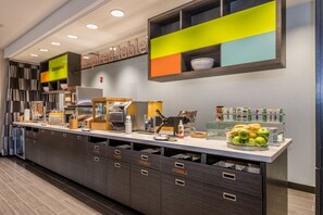 Zona cuina moderna amb barra de petitdejuni, amb la inscripció 'inspired table', que inclou una cafetera, torradora i diversos aliments per esmorzar.