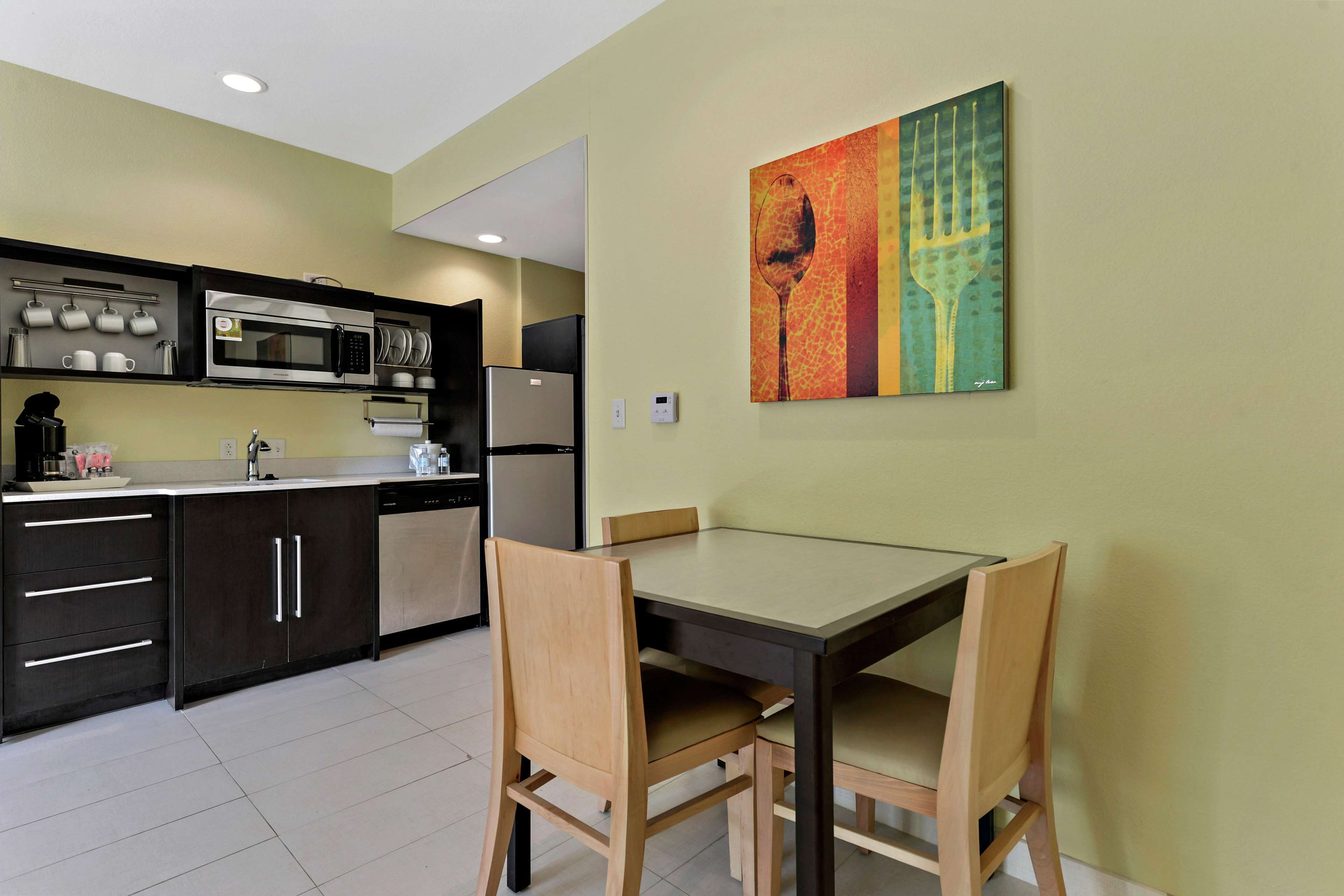 A modern kitchen with dark cabinets, a microwave, and a dining table with chairs.