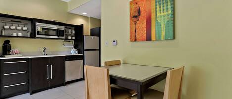 A modern kitchen with dark cabinets, a microwave, and a dining table with chairs.