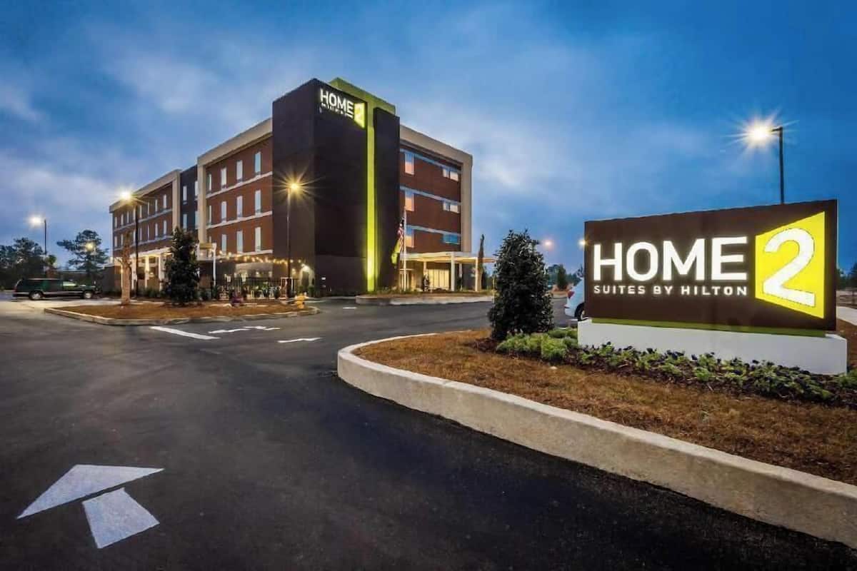 Hotellissa on kyltti, jossa lukee ”HOME 2 Suites by Hilton”, ja rakennuksessa on useita kerroksia sekä selkeästi erottuva pääsisäänkäynti.
