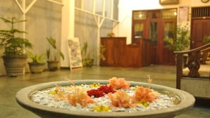 A reception area with a decorative water feature in the foreground, potted plants, and a wooden reception desk. - Hotel Baywatch (Unawatuna)