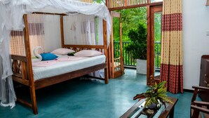 A wooden four-poster bed with a canopy, a small table with a plant, and a view of greenery through a glass door. - Hotel Baywatch (Unawatuna)