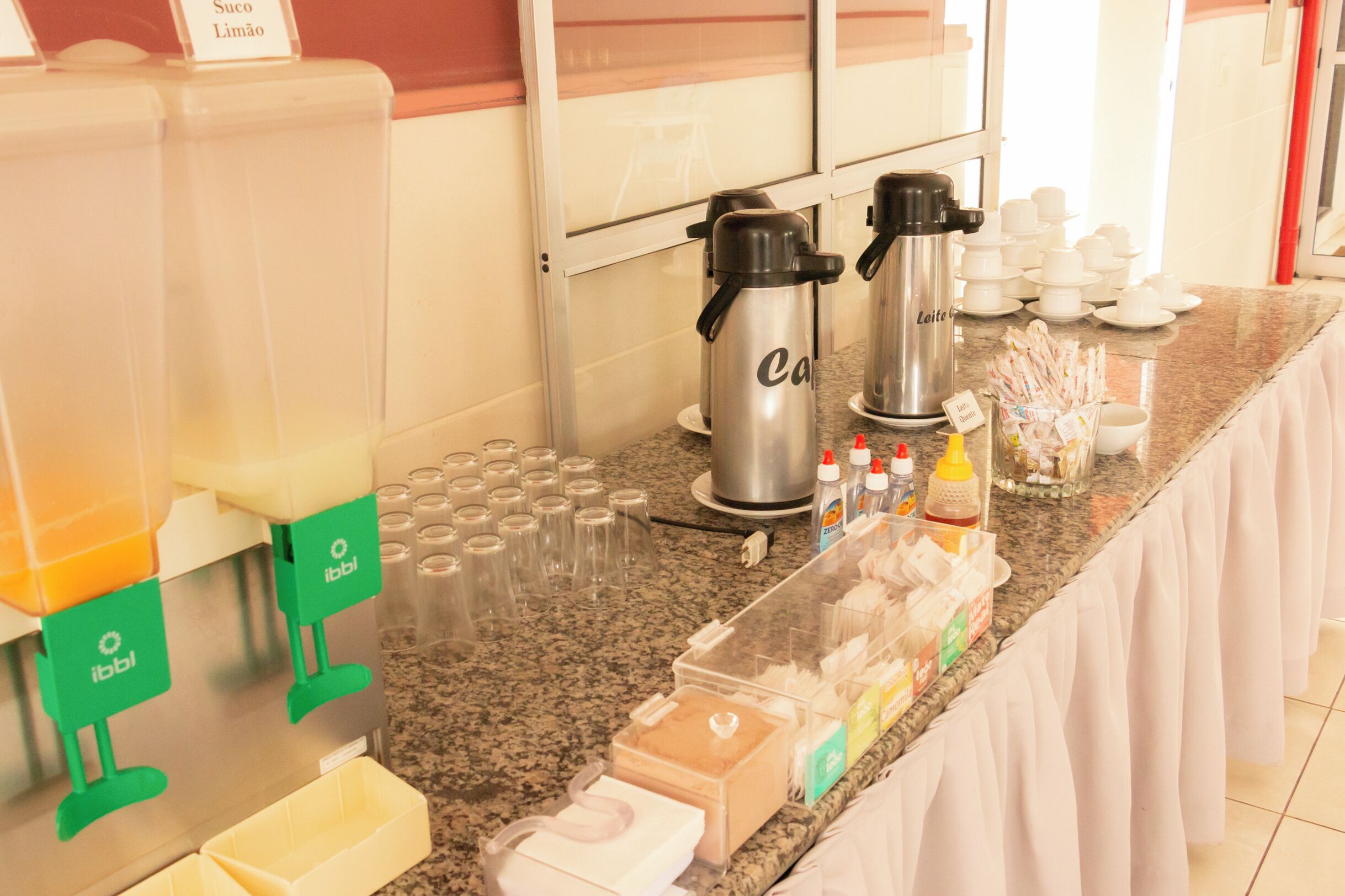 Una mesa de buffet con cafeteras, tazas y aderezos.