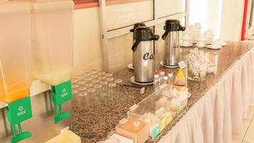 Una mesa de buffet con cafeteras, tazas y aderezos.