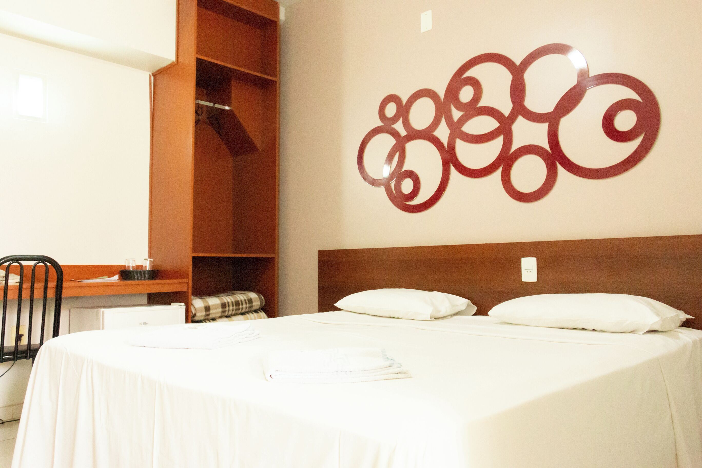 Une chambre d’hôtel avec un lit, un bureau et une armoire.