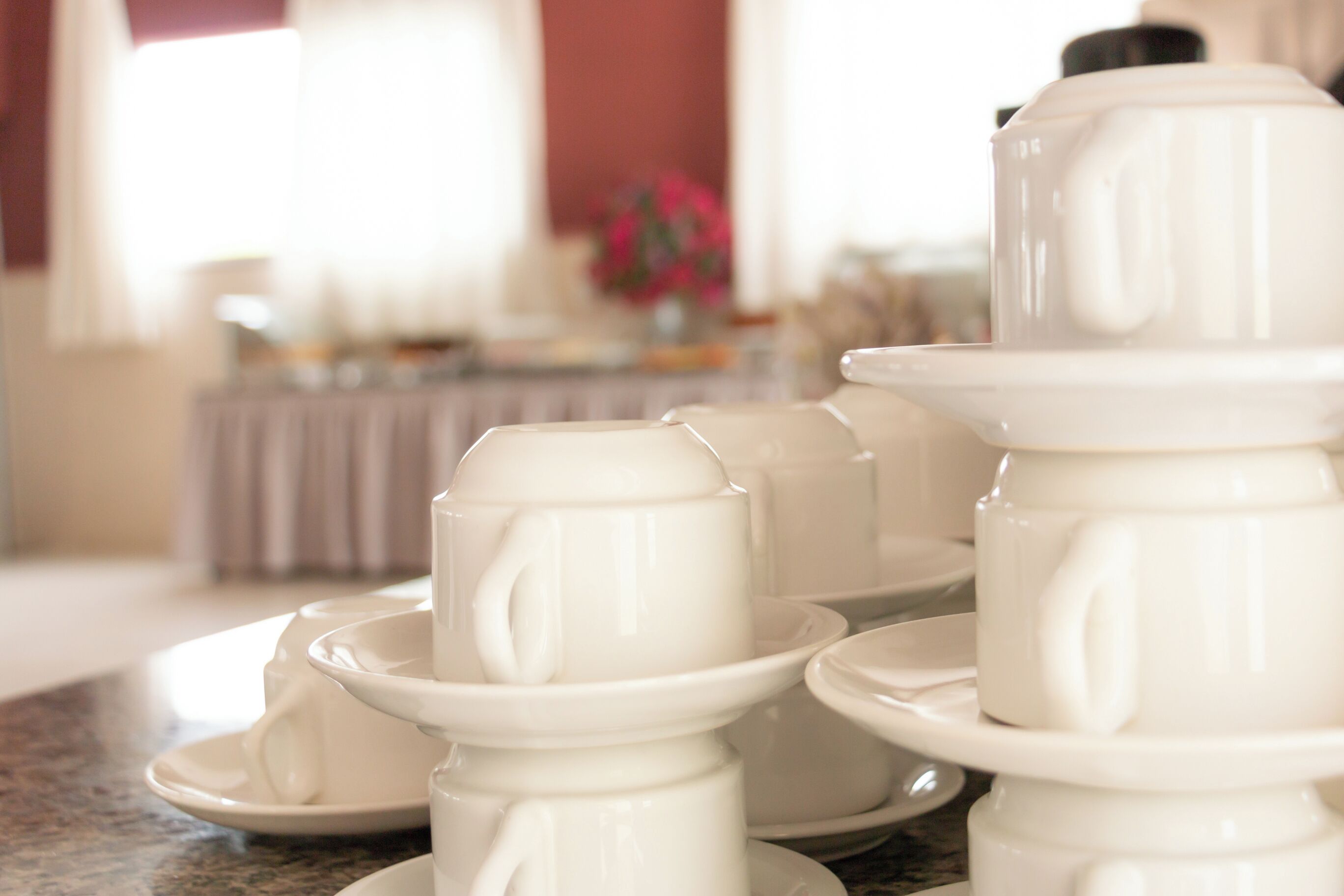 A stack of white ceramic tea sets on a marble countertop.