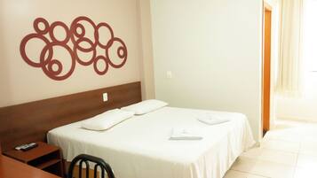 A hotel room with a bed, a desk, a chair, and a wall decoration.