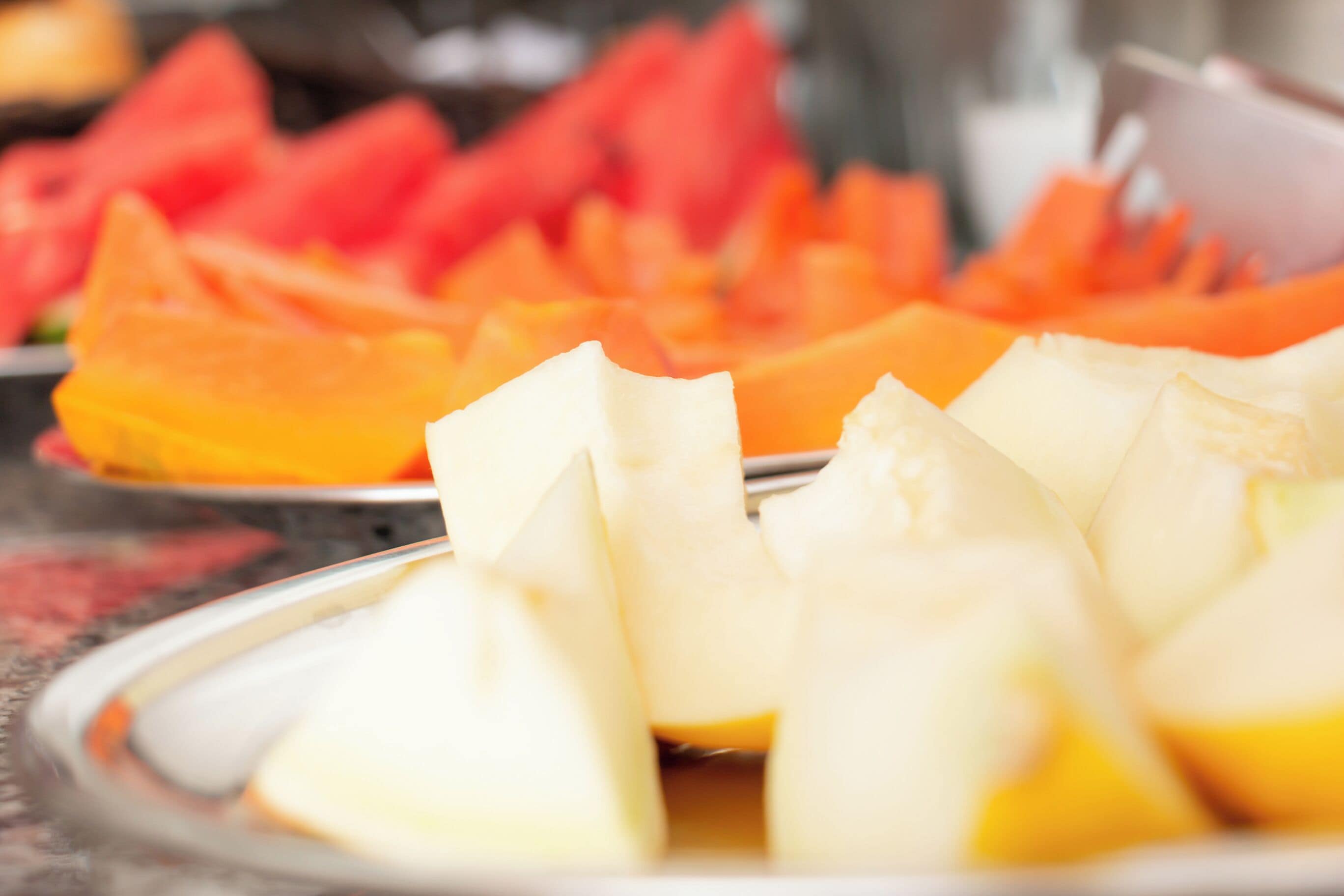 En tallerken med skiveskåret frugt, herunder vandmelon og cantaloupe.