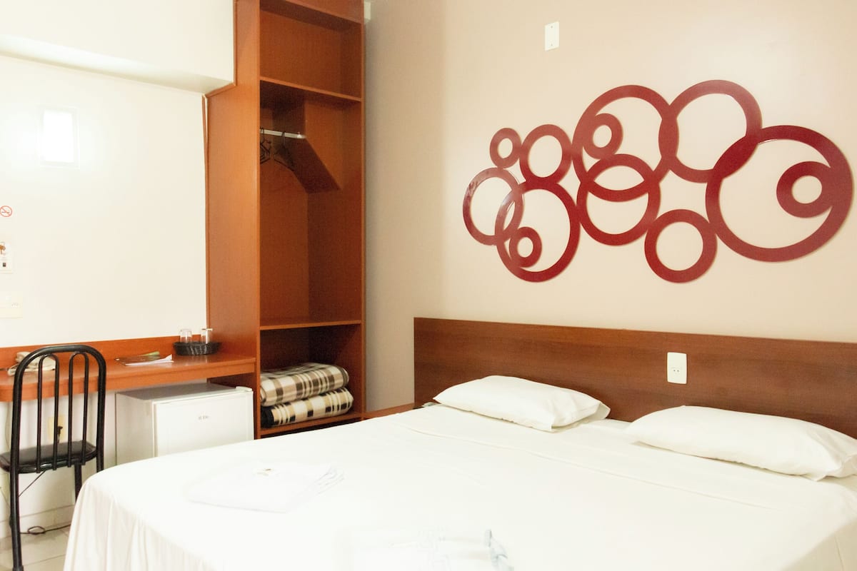 A hotel room with a bed, a desk, and a wardrobe.