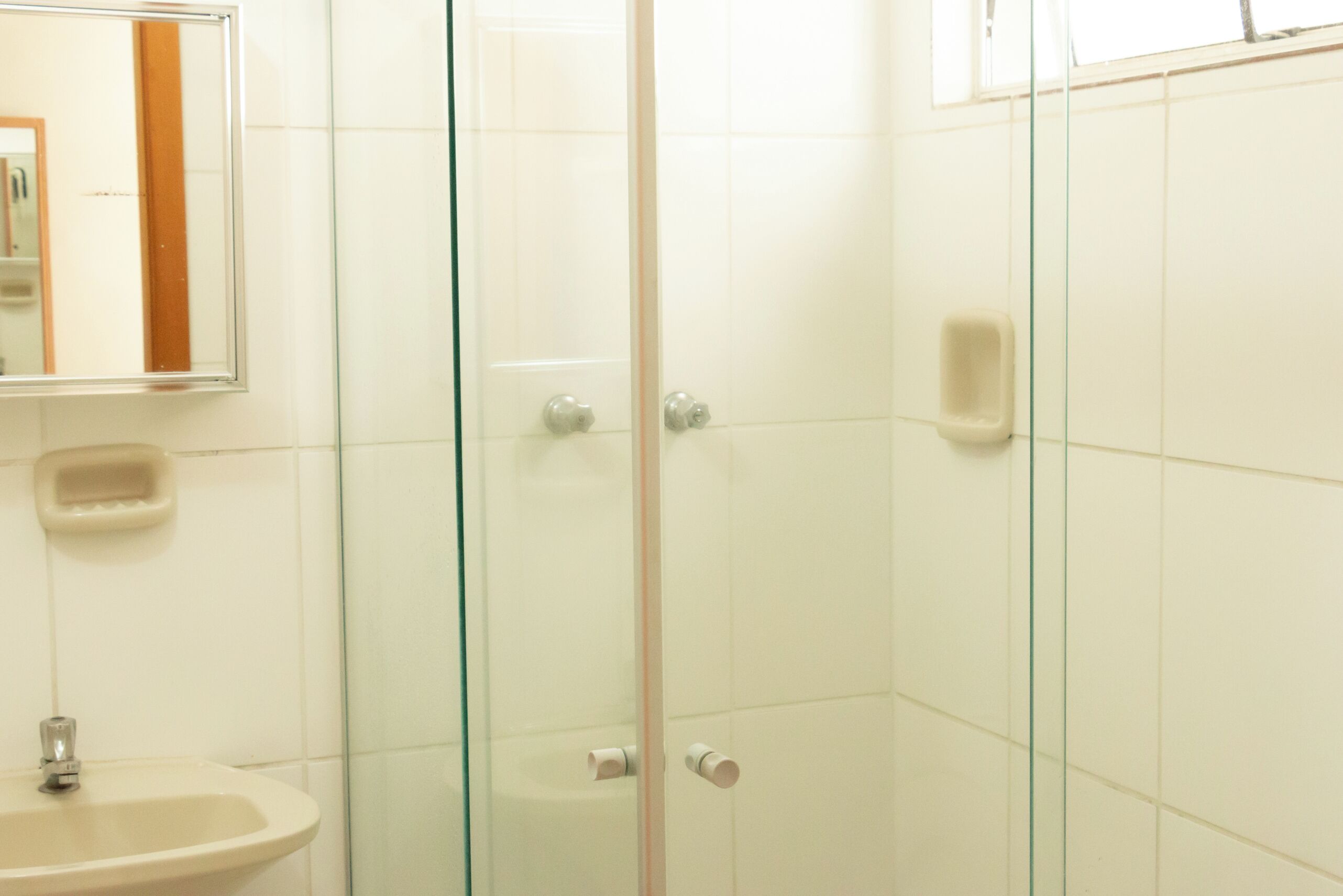 Un baño con cabina de ducha de vidrio, un lavabo y un espejo.