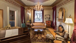 Uma sala ampla com um piano, um sofá, lareira e decoração requintada.