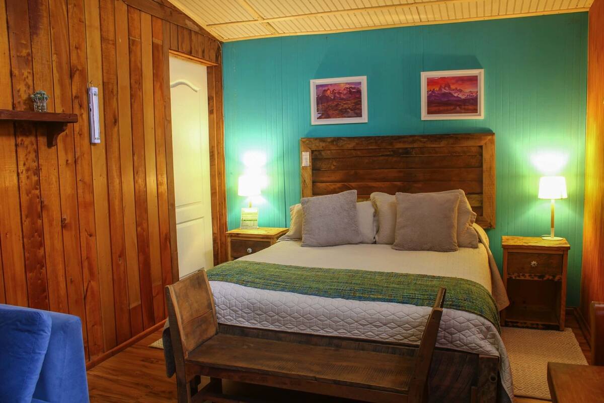 A wooden-paneled room with a bed, two wall-mounted lamps, and a small shelf with a decorative item.