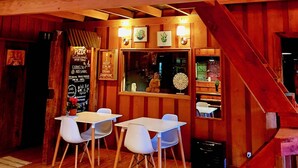 Un interior de madera con un área de comedor, un menú en pizarra y una escalera.