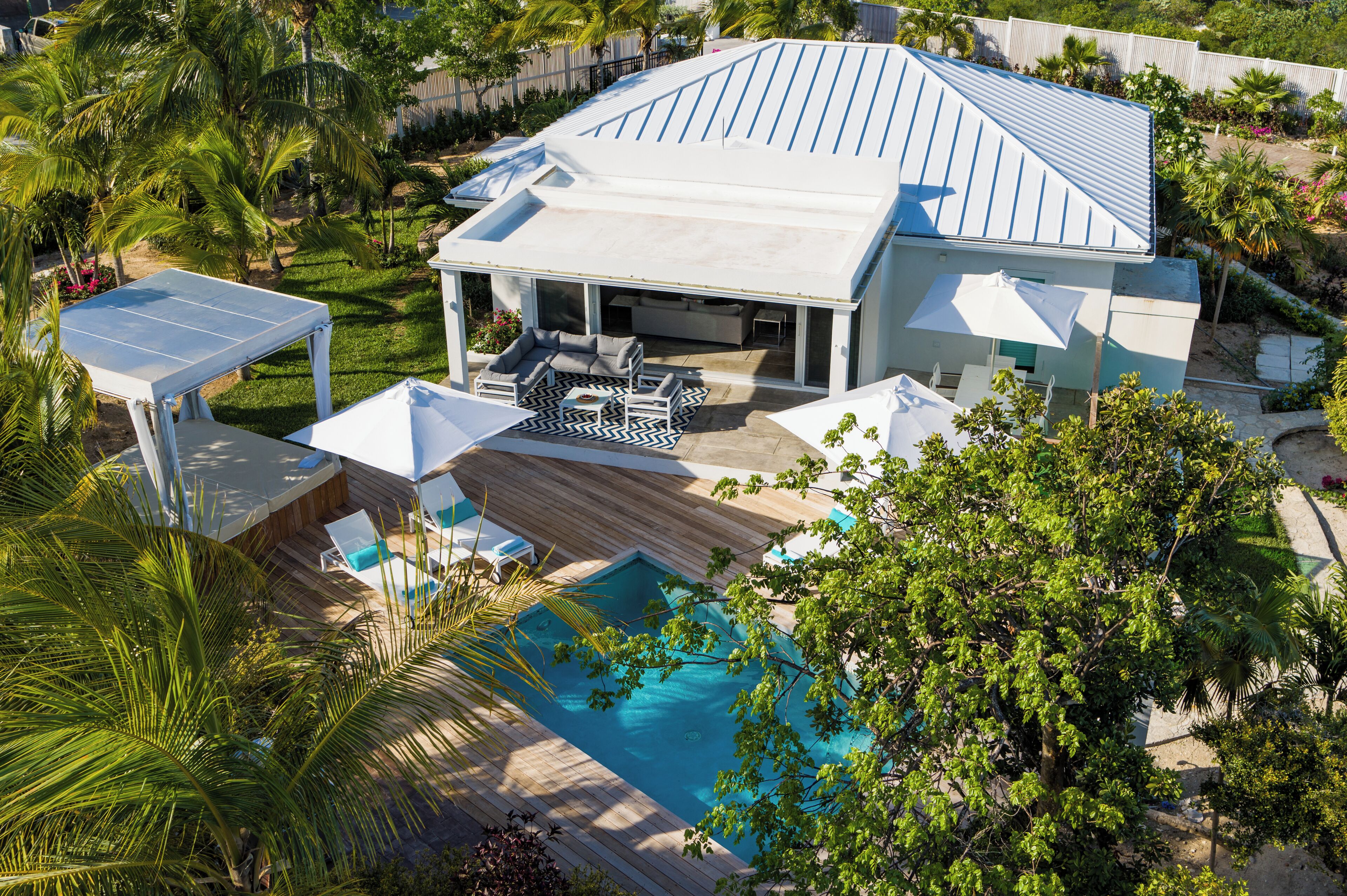 A modern house with a large pool, covered patio, and lush garden.