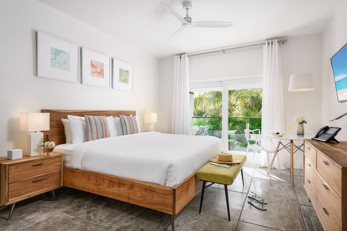 Ein modernes Schlafzimmer mit einem hölzernen Bett, Nachttischen, einem Schreibtisch und Blick ins Grüne.