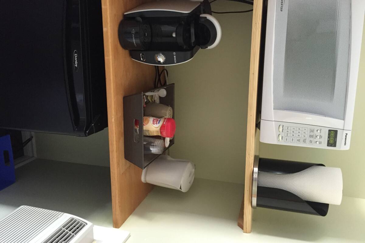 A kitchen with a microwave, a coffee maker, and a small storage cabinet.