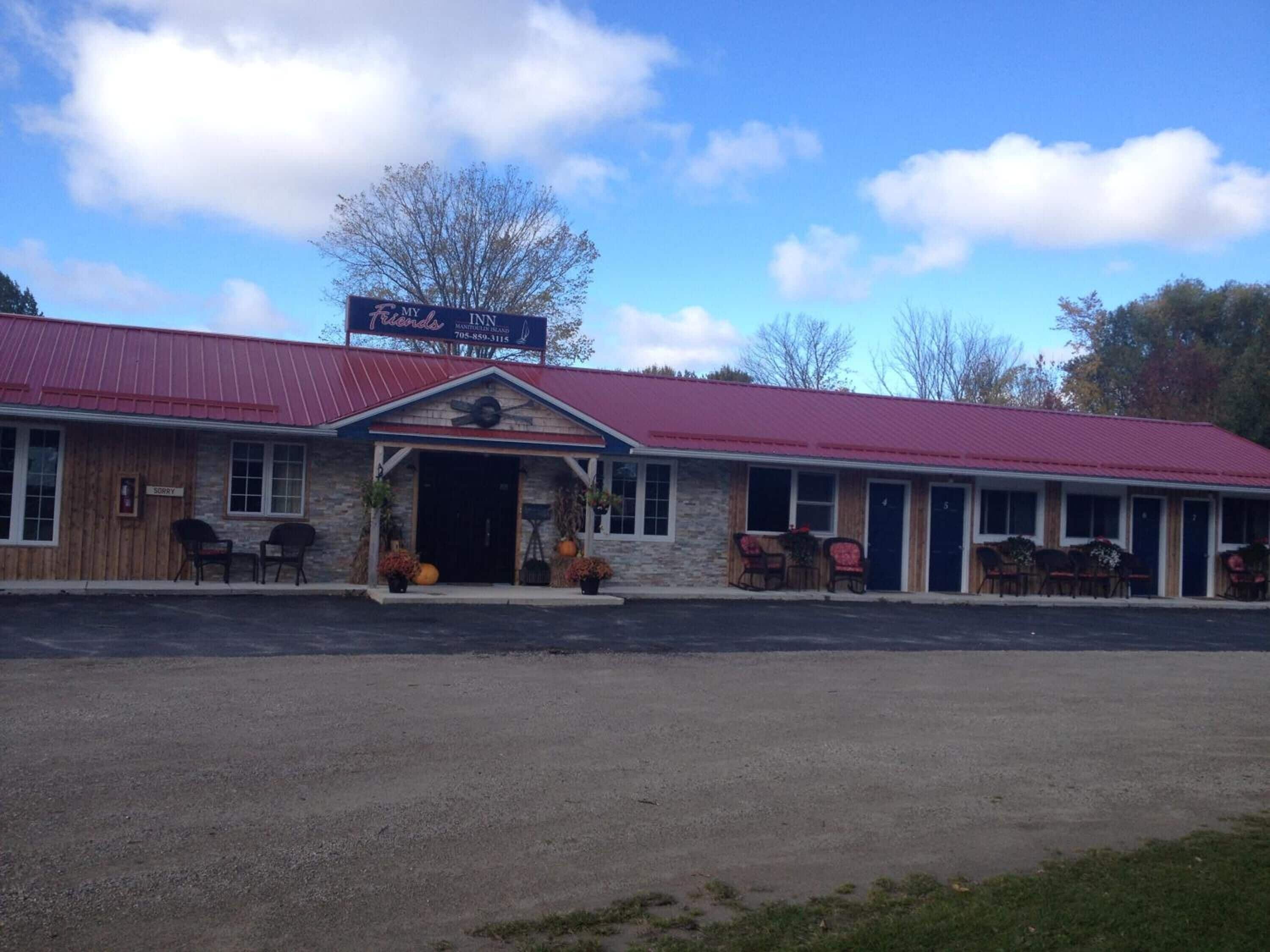 A motel with a red roof and stone facade, featuring a 'My Friends' sign and a 'Sorry' sign on the door.