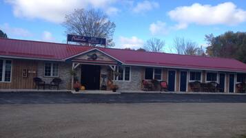 A motel with a red roof and stone facade, featuring a 'My Friends' sign and a 'Sorry' sign on the door.