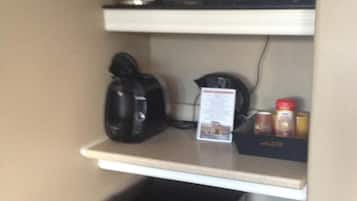 A kitchenette with a microwave, coffee maker, and a trash bin.