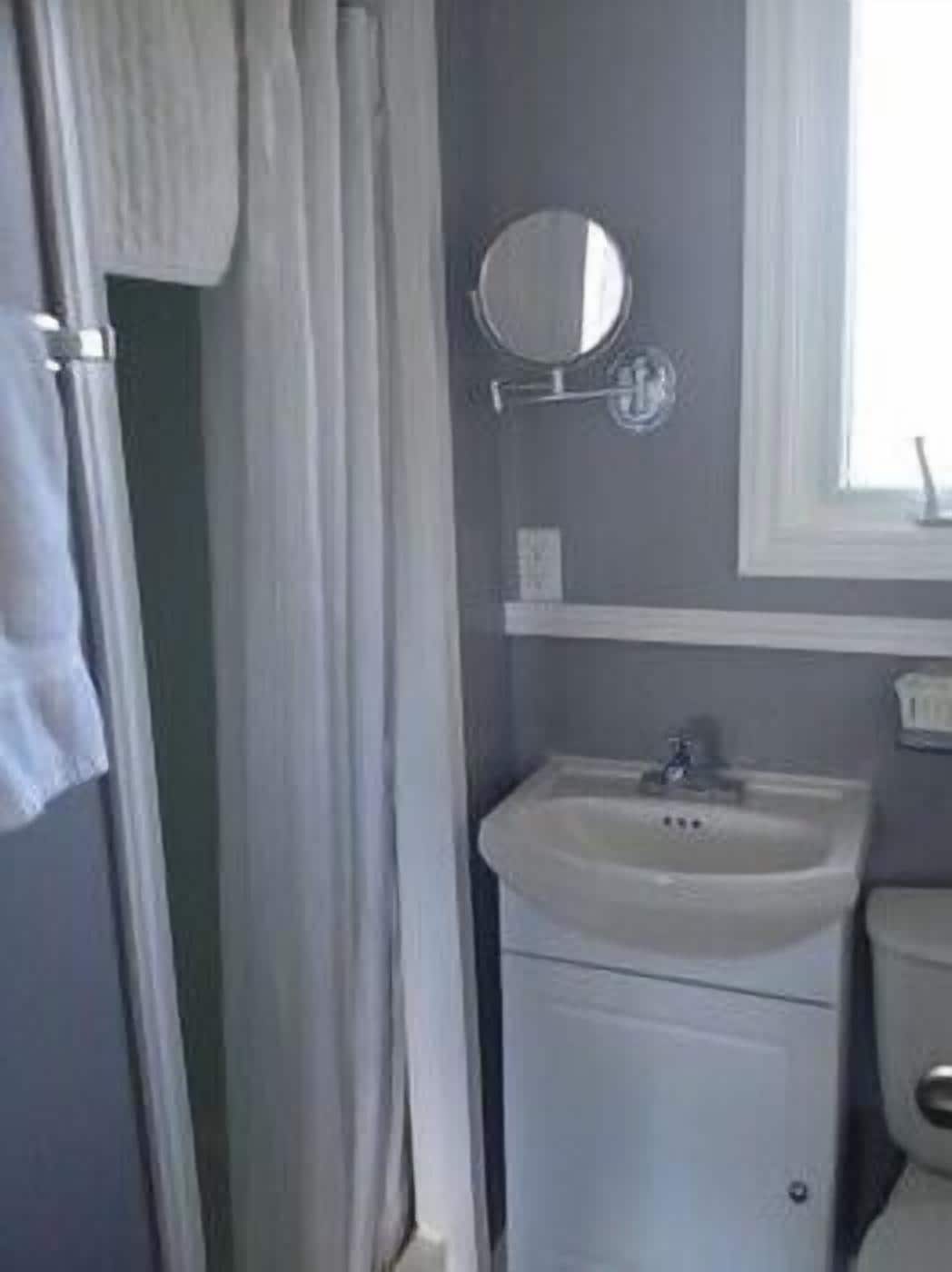 Un baño con lavamanos blanco, un espejo y un inodoro.