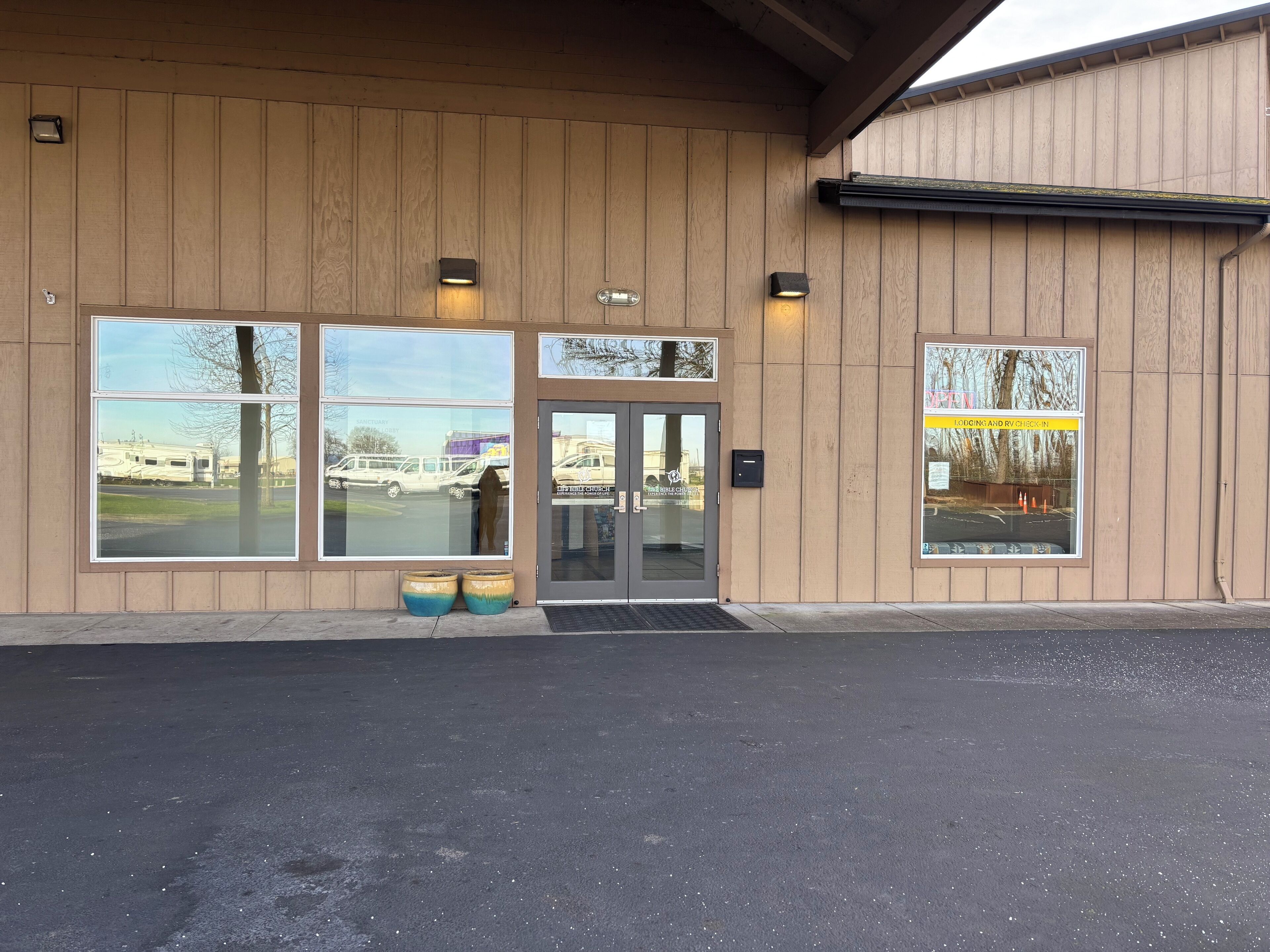 A building with large windows, a door, and two planters.