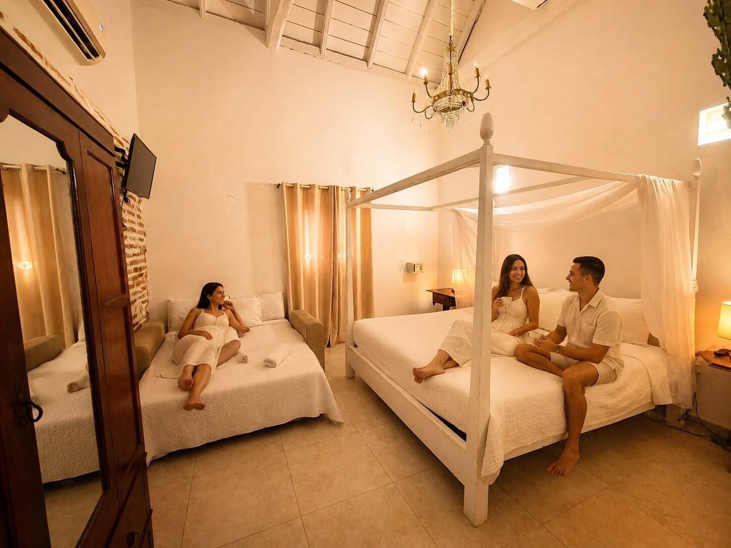 A hotel room with a four-poster bed, a separate sofa bed, and a television mounted on the wall.