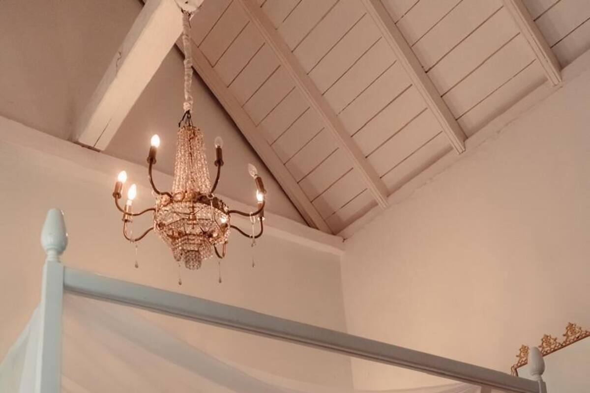 Un lit à baldaquin, un lustre et une table de chevet avec une lampe.