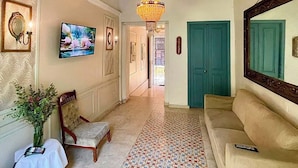 Un couloir avec des carreaux décoratifs, un lustre, un canapé et un fauteuil.