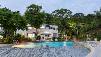 Una piscina al aire libre, sombrillas, sillones reclinables de piscina