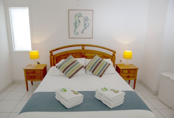 A neatly made bed with two pillows, a blue bedspread, and two bedside tables with lamps. - Green9 Hotel & Beach Resort Same (Tonchigüe)