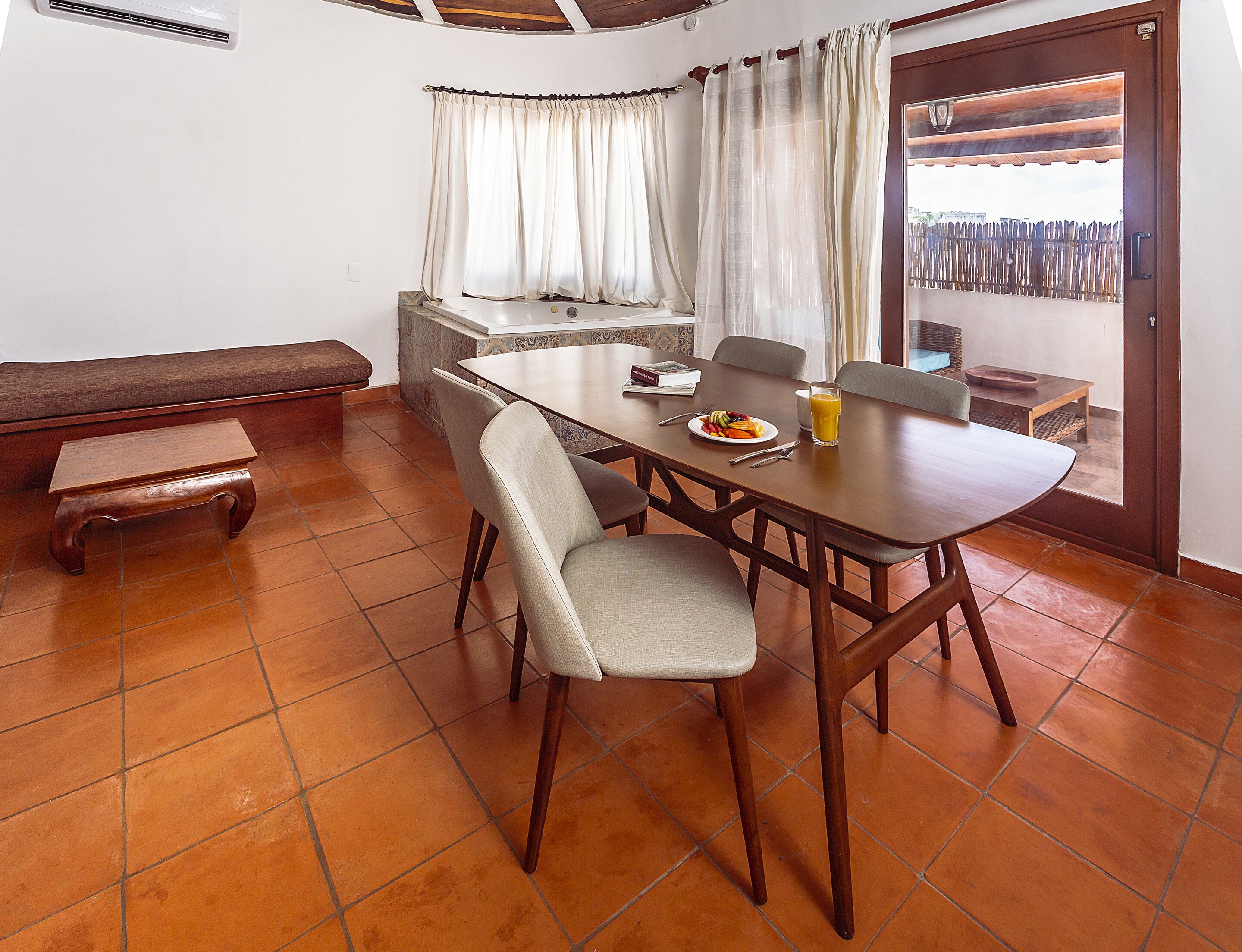 A dining area with a wooden table, chairs, a bench, and a breakfast setting.