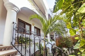 A white building with a balcony, a staircase with a wrought iron railing, and various plants. - Fabiola Condo Hotel (Playa del Carmen)
