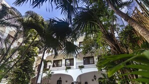 A multi-story building with balconies, surrounded by lush tropical vegetation. - Fabiola Condo Hotel (Playa del Carmen)