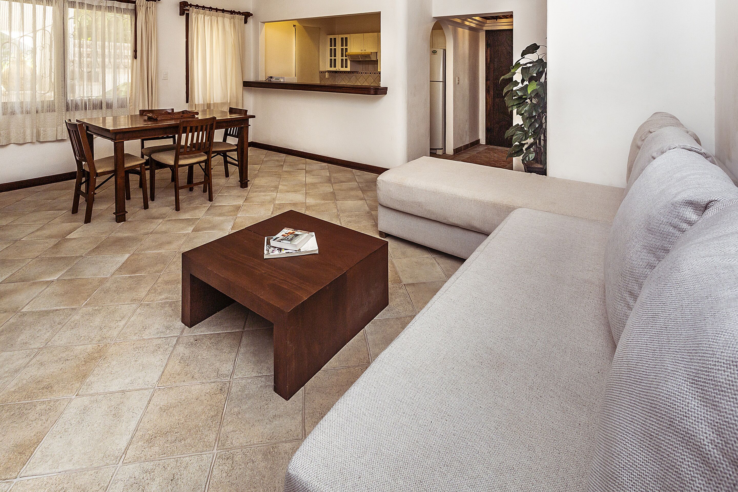 A living room with a sofa, a coffee table, and a dining area with chairs and a table.