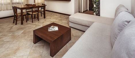A living room with a sofa, a coffee table, and a dining area with chairs and a table.